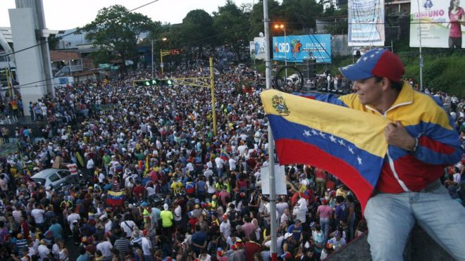 Сторонник оппозиции держит национальный флаг Венесуэлы во время празднования в Сан-Кристобале