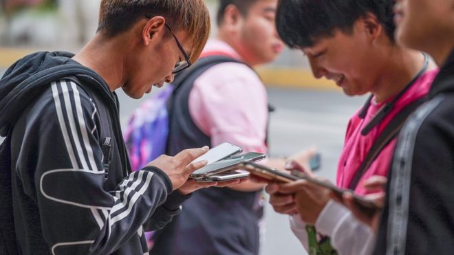 Jóvenes viendo el celular en Shanghai.