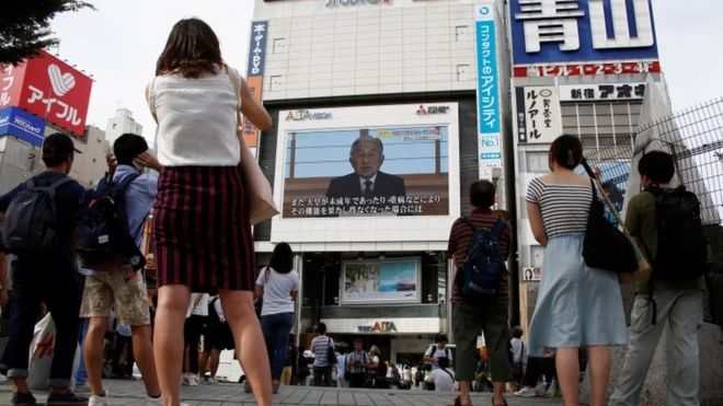 Люди смотрят большой экран с видеообращением японского императора Акихито в Токио, Япония, 8 августа 2016 г.