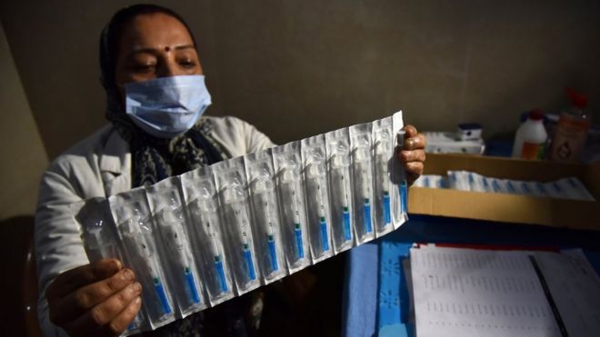 Health care worker in Jammu holds syringes with a mock Covid vaccine (2 Jan)