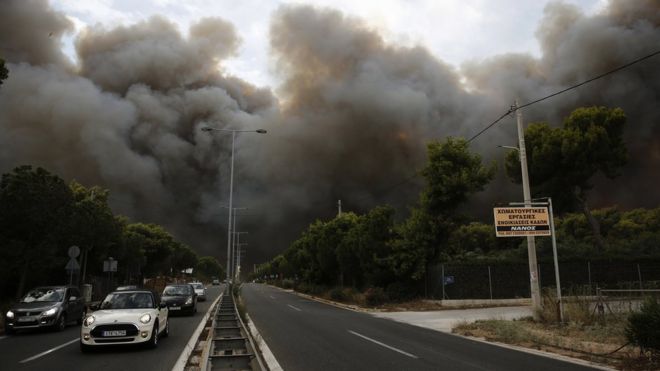 Дым поднимается над проспектом во время лесного пожара в Нео Вутса, северо-восточном пригороде Афин, Греция, 23 июля 2018 года.