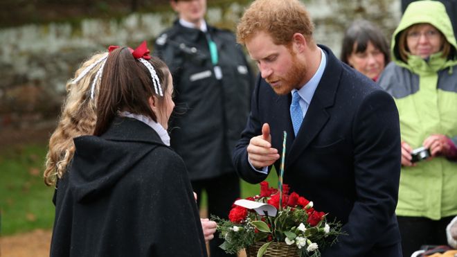 Принц Гарри принимает цветы во время посещения церкви в Рождество 2015 года
