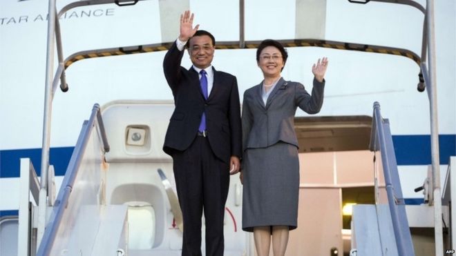 Премьер-министр Китая Ли Кэцян (слева) и его жена Чэн Хун машут официальным лицам по прибытии в аэропорт имени Шарля де Голля в Руасси, пригород Парижа, 29 июня 2015 года.