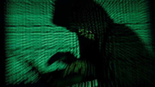 Imagen de una hombre con capucha usando una computadora.