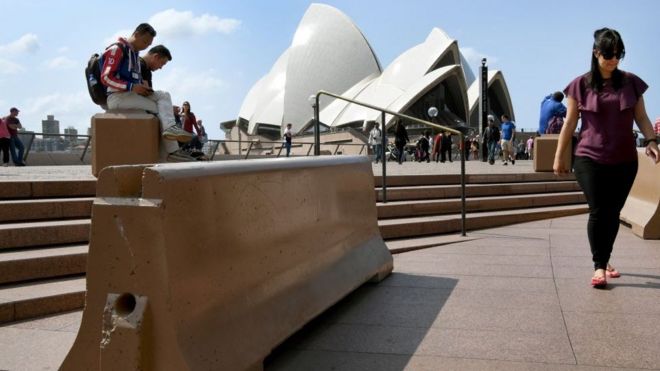 Туристы проходят мимо кнехтов в Сиднейском оперном театре, предназначенном для защиты от нападений транспортных средств
