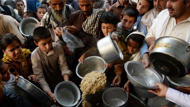 Афганские дети держат посуду в ожидании получения еды, пожертвованной частной благотворительной организацией для нуждающихся в священный для мусульман месяц Рамадан в городе Джалал-Абад 9 июня 2016 года