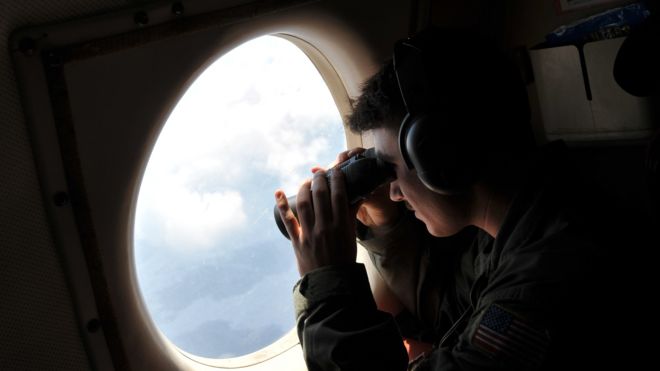 Search plane crew member uses binoculars to look through window of US patrol aircraft searching for missing EgyptAir flight. Sunday, May 22, 2016