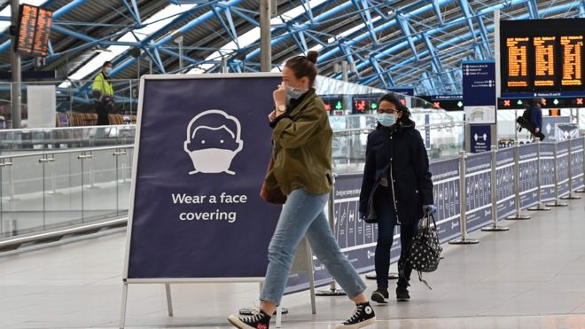 Знак предписывает пассажирам «надевать маску» на вокзале Ватерлоо в центре Лондона 8 июня 2020 года, когда начинается запланированный правительством Великобритании 14-дневный карантин для прибывающих из-за границы, чтобы ограничить распространение нового коронавируса COVID-19.