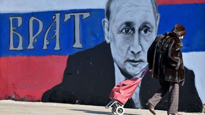 Una mujer pasa por delante de un mural con la cara de Putin y la palabra "hermano", en Belgrado, en marzo de 2022.