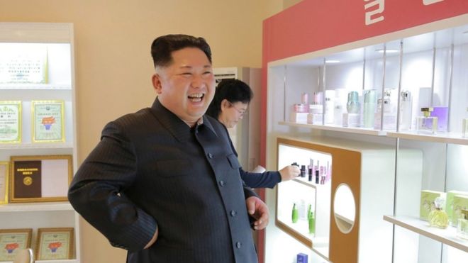 Kim Jong Un smiles near a pink-branded selection of cosmetics