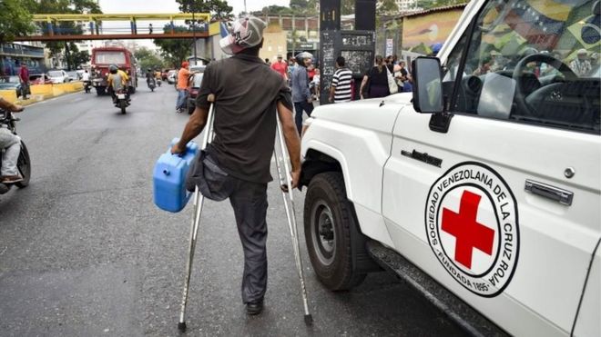Мужчина уходит после получения барабана для сбора воды и таблеток для очистки воды от членов Венесуэльского Красного Креста в окрестностях Катиа в Каракасе, Венесуэла, 16 апреля 2019 года