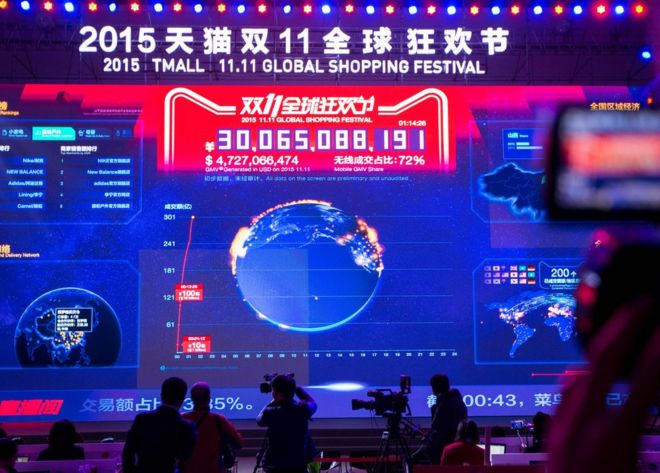 Люди фотографируют большой экран, показывающий общий объем валовых товаров, показатель продаж, превышающий 10 миллиардов юаней в 00:12 и 28 секунд во время гала-концерта Tmall 11:11 Global Shopping Festival 2015 года в Пекине 11 ноября 2015 года