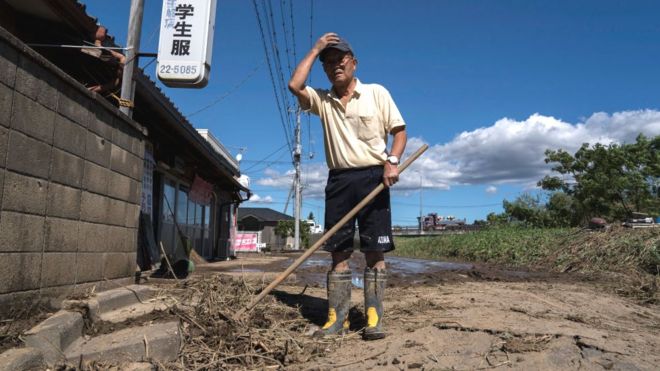 Мужчина очищает свой магазин от грязи после прохождения тайфуна «Хагибис»