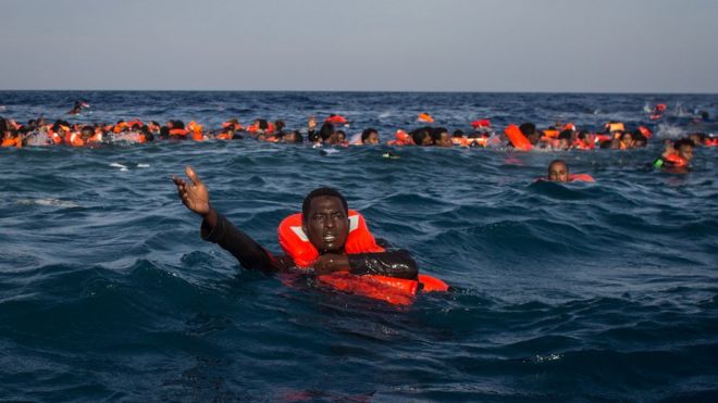 Беженцы и мигранты видят, как они плавают и кричат ??о помощи членов экипажа с корабля «Феникс» на Морской станции помощи мигрантам (MOAS) после того, как 24 мая 2017 года из Лампедузы перевезено более 500 человек, перевезенных из Лампедузы