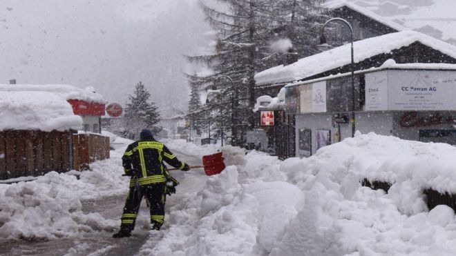 Workers remove snow beside the Zermatt train station after heavy snowfall and avalanches trapped more than 13,000 tourists at Zermatt, 9 January