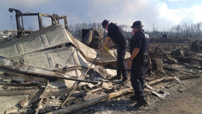 Emergency workers inspect burnt-out buildings in Fort McMurray