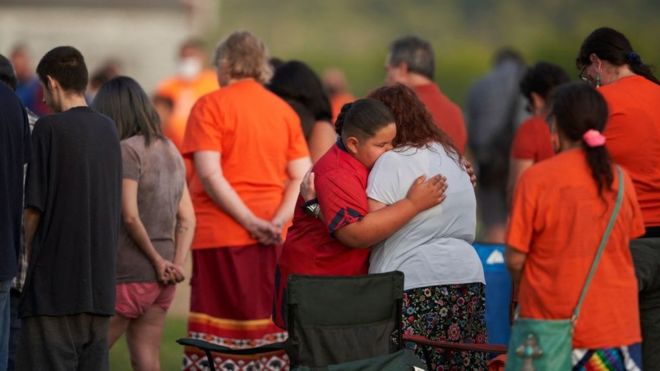 People hug during a vigil in a field where human remains were found in unmarked graves at the site of the former Marieval Indian Residential School on the Cowessess First Nation in Saskatchewan on June 26, 2021