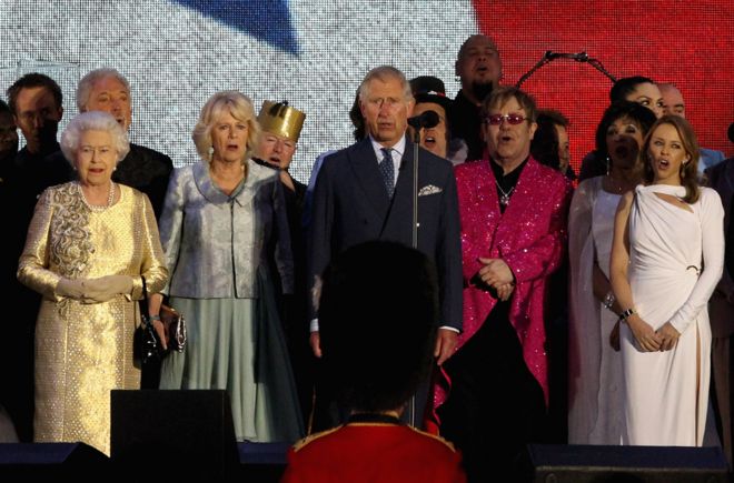 Королева Елизавета II, герцогиня Корнуоллская, Принц Уэльский, сэр Элтон Джон, Дам Ширли Бэсси и Кайли Миноуг на сцене во время исполнения государственного гимна во время концерта Diamond Jubilee в Букингемском дворце 4 июня 2012 года