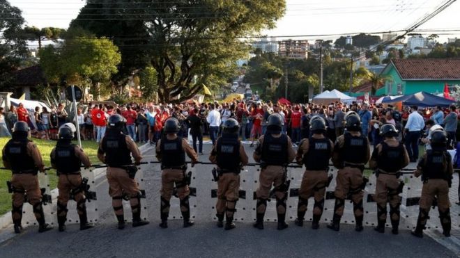 ОМОН блокирует вход в штаб-квартиру Федеральной полиции, поскольку сторонники бывшего президента Бразилии Луиса Инасиу Лула да Силва проводят акцию протеста в Куритибе, Бразилия, 8 апреля 2018 года.