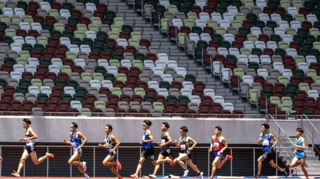 Hombres corriendo por un estadio.