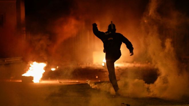 A demonstrator kicks a tear gas canister