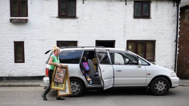 Женщина кладет картины в машину