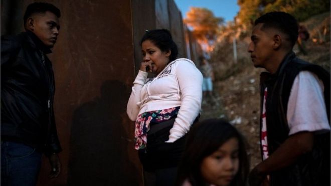 Мигранты из Гондураса стоят у пограничной ограды в Тихуане, Мексика, 2 декабря 2018 года