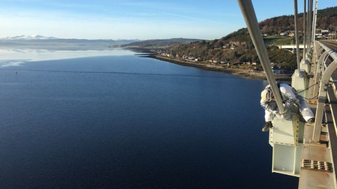 Un técnico trabajando sobre el puente Kessock, cerca de Inverness, con el Mar del Norte de fondo.