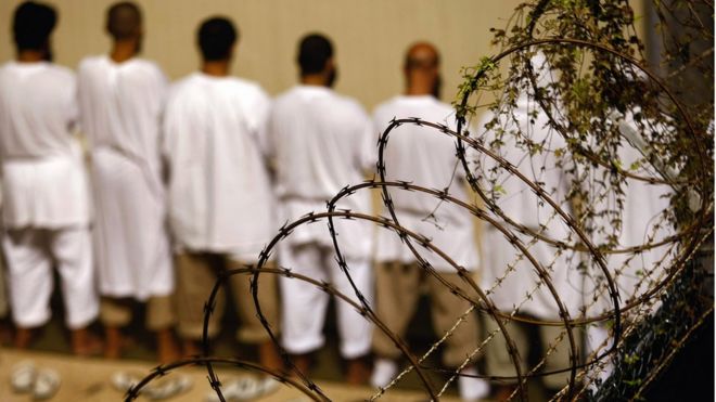 Заключенные стоят во время ранней утренней исламской молитвы в военной тюрьме США за «вражеских бойцов» 28 октября 2009 года в заливе Гуантанамо, Куба.