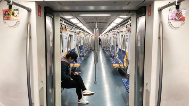 Мужчина в маске сидит в вагоне поезда