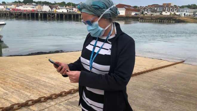Сотрудница Национальной службы здравоохранения Великобритании Анни Адамс рассматривает новое приложение NHS для отслеживания контактов с людьми, потенциально инфицированными коронавирусной болезнью (COVID-19), испытываемой на острове Уайт,