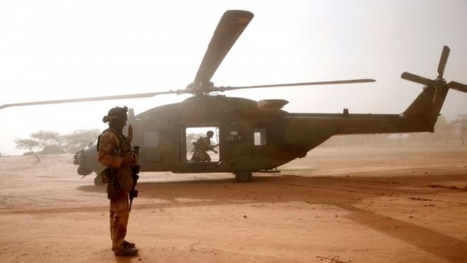 A French soldier stands in front of military helicopter in Mali