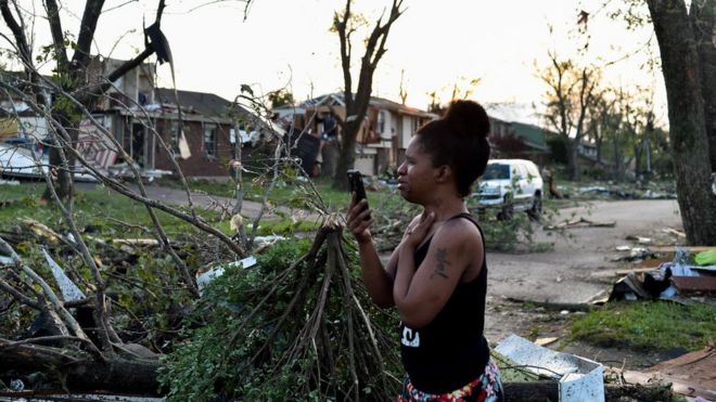 Женщина снимает повреждения домов после удара торнадо