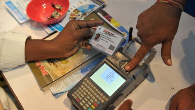 An Indian visitor gives a thumb impression to withdraw money from his bank account with his Aadhaar card.