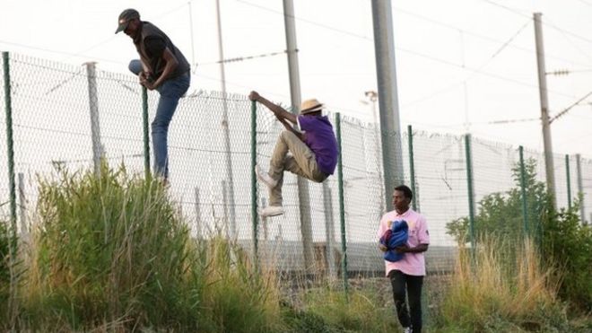 Мигранты перелезают через забор в Кокель возле Кале