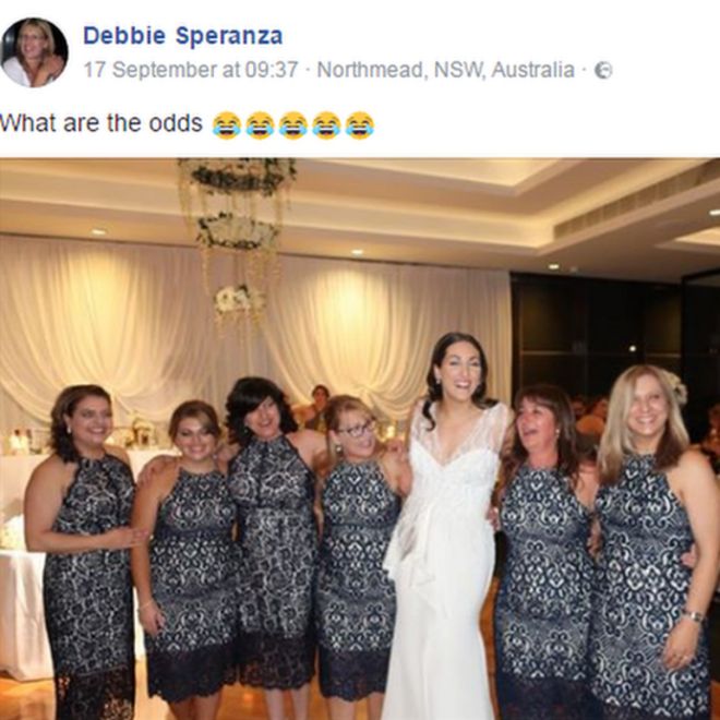 Шесть гостей свадьбы в одинаковых платьях позируют для фотографирования с невестой