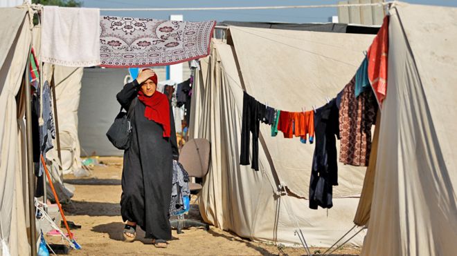 A Palestinian woman walks at a tent camp at a United Nations-run centre, after Israel's call for more than 1 million civilians in northern Gaza to move south, in Khan Younis in the southern Gaza Strip, October 26, 2023.