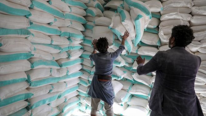 Workers handle sacks of wheat flour at a World Food Programme food aid distribution centre in Sanaa, Yemen February 11, 2020