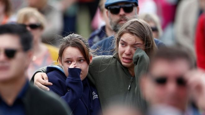 Две девочки плачут в толпе на поминальной службе жертвам нападения мечети