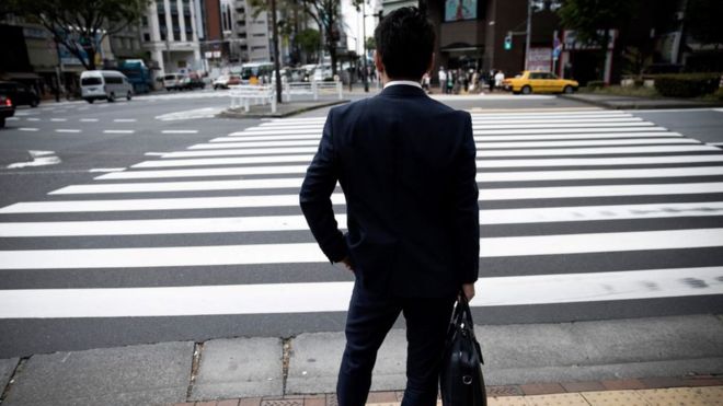 Мужчина стоит перед улицей в центре Токио 27 апреля 2017 года