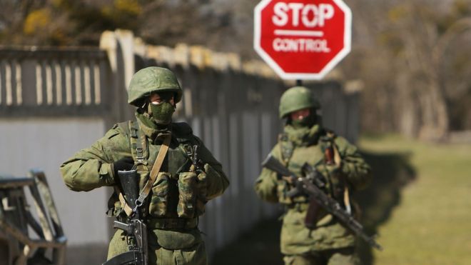 Вооруженные солдаты без опознавательных знаков хранят охрану возле украинской военной базы в городе Перевальне близ крымского города Симферополя 17 марта 2014 года