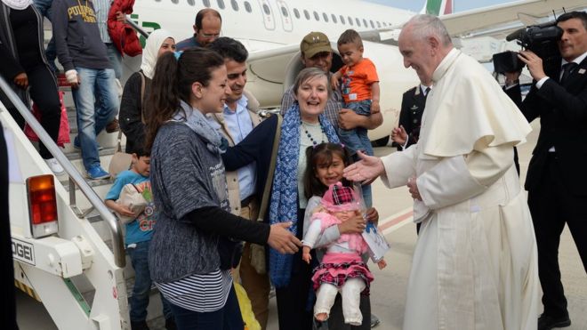 Папа Франциск приветствует группу сирийских беженцев после приземления в аэропорту Чампино в Риме после посещения лагеря беженцев Мория 16 апреля 2016 года на греческом острове Лесбос. Двенадцать сирийских беженцев сопровождали папу Франциска во время его обратного рейса в Рим после его визита на Лесбос в субботу и будут размещены в Ватикане, сказал Святой Престол.