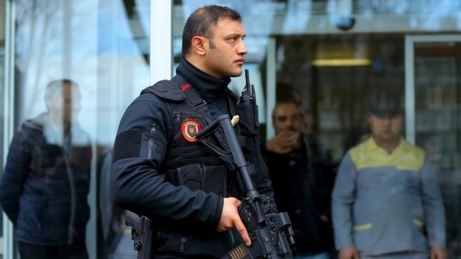 Турецкий полицейский стоит на страже, так как премьер-министр Турции Ахмет Давутоглу и министр внутренних дел Германии Томас де Мезьер посещают раненых во время теракта во вторник на площади Султанахмет в Стамбуле (13 января 2016 года)