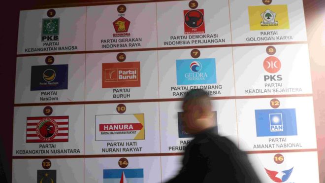 Petugas keamanan melintas di depan poster lambang partai politik peserta Pemilu 2024 saat pendaftaran bakal calon anggota DPRD di KPU Kediri, Jawa Timur, Rabu (10/05)