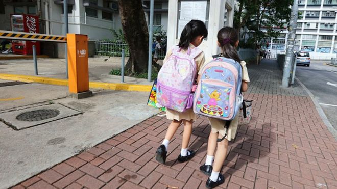 Children walk along a street in Hong Kong
