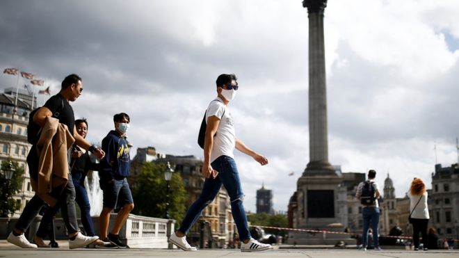 Люди в защитных масках идут по Трафальгарской площади