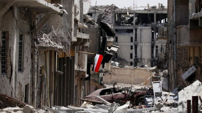 Иракский флаг виден среди разрушенных зданий во время боевых действий между иракскими вооруженными силами и боевиками Исламского государства в Старом городе Мосула (4 июля 2017 года)