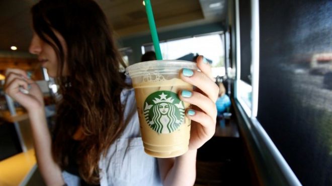 A patron holds an iced beverage with a straw, at a Starbucks coffee store in Pasadena, California