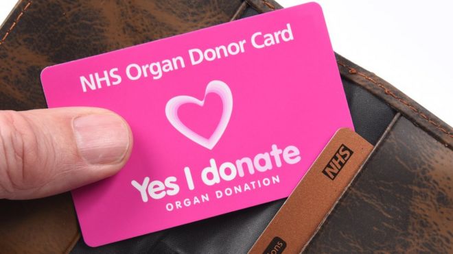 Донора органов NHS держат перед кошельком