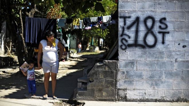 Mujer y niño junto a un grafiti del Barrio 18 en la colonia Valle del Sol en Apopa, El Salvador. (Foto: José Cabezas / Getty Images)